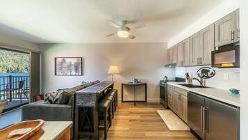 A modern kitchen with wooden cabinets, a stainless steel refrigerator, and a dining area with a bench and table.