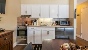A compact kitchen with white cabinets, a stove, microwave, and a dishwasher. - Charming Deluxe Studio w/Lake View #246 at Donner Lake Village (Truckee)