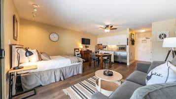 A compact living space with a bed, a sofa, a dining table, and a kitchenette.