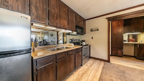 A kitchen with wooden cabinets, stainless steel appliances, a microwave, and a sink.