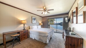 A bedroom with a bed, bedside tables, a desk, a chair, a ceiling fan, and a balcony with a view.