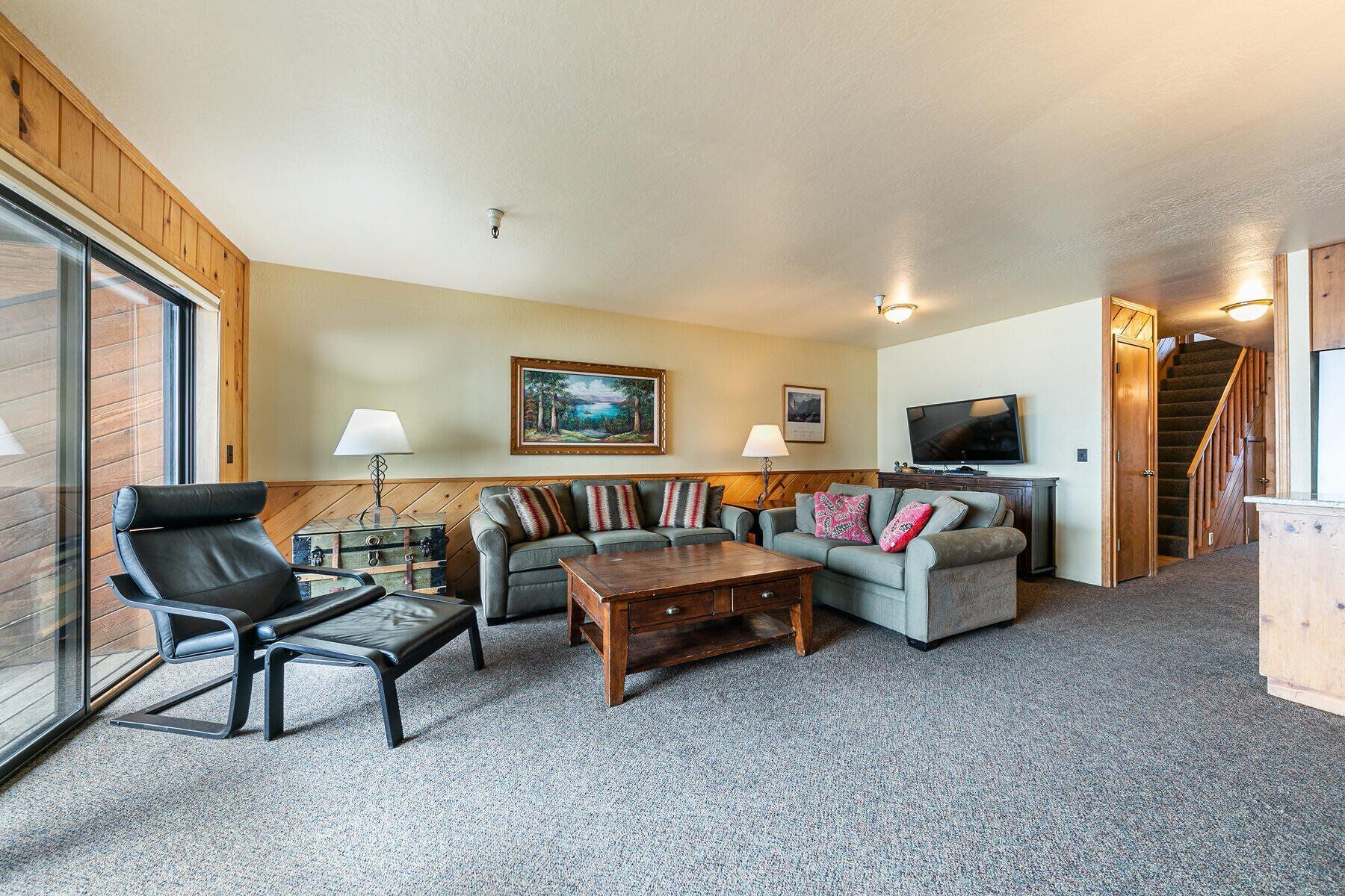 A cozy living room with a sofa set, a wooden coffee table, and a television.