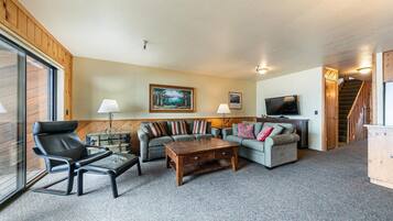 A cozy living room with a sofa set, a wooden coffee table, and a television.