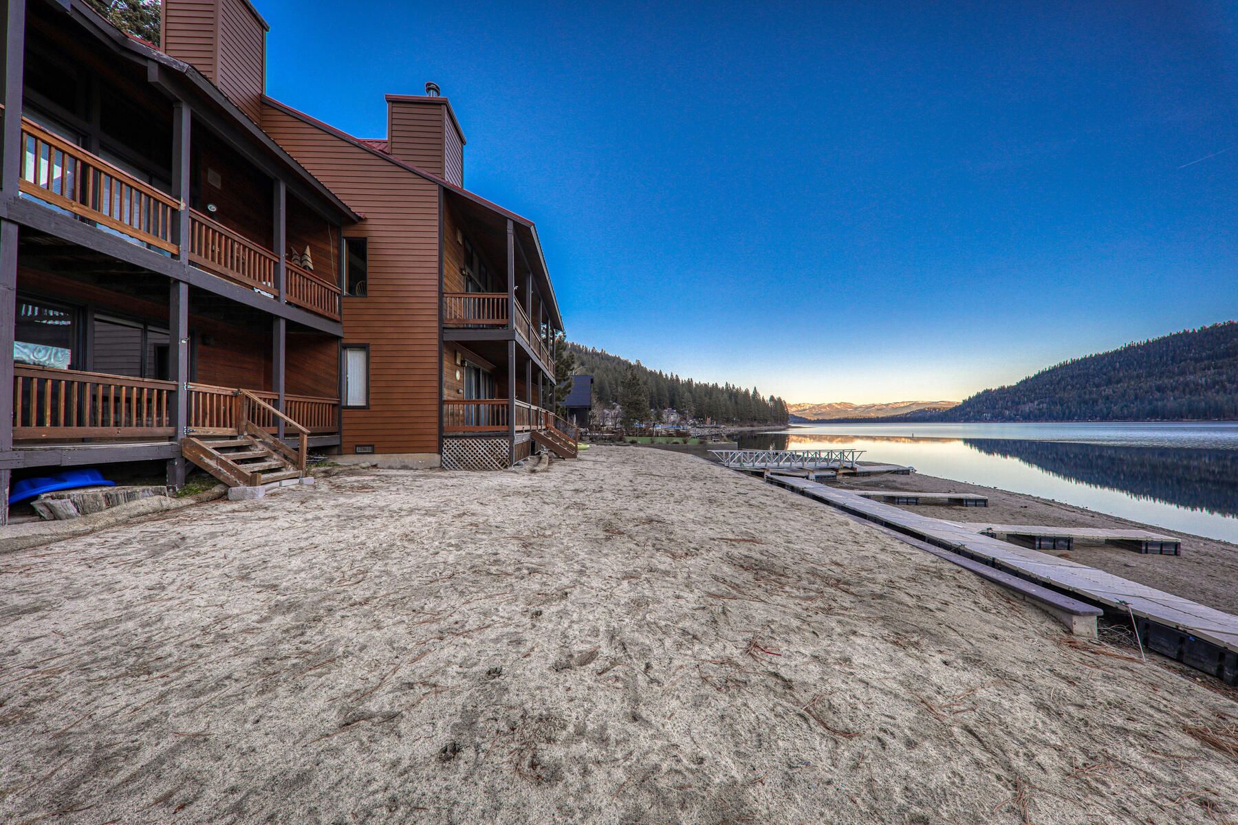 A lakeside property with a wooden building, a dock, and a clear view of the lake.