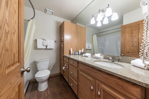 A bathroom with a toilet, wooden cabinets, a sink, and a mirror.