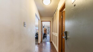 Un couloir étroit, doté d’un plancher en bois, mène à une pièce qui possède une porte.