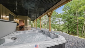 A hot tub with a "Made in U.S.A." label, wooden beams, and a view of a forest.