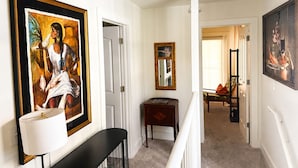 A hallway with a framed painting, a lamp, a small table, and a mirror. - Mermaid's Muse - Includes GOLF CART! Close to beach & downtown Ocean Springs! (Ocean Springs)