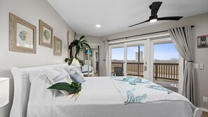 Une chambre à coucher avec un lit, un ventilateur de plafond et une vue sur l’extérieur.