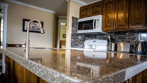 Una cocina con armarios de madera, un microondas blanco y un hervidor de acero inoxidable.