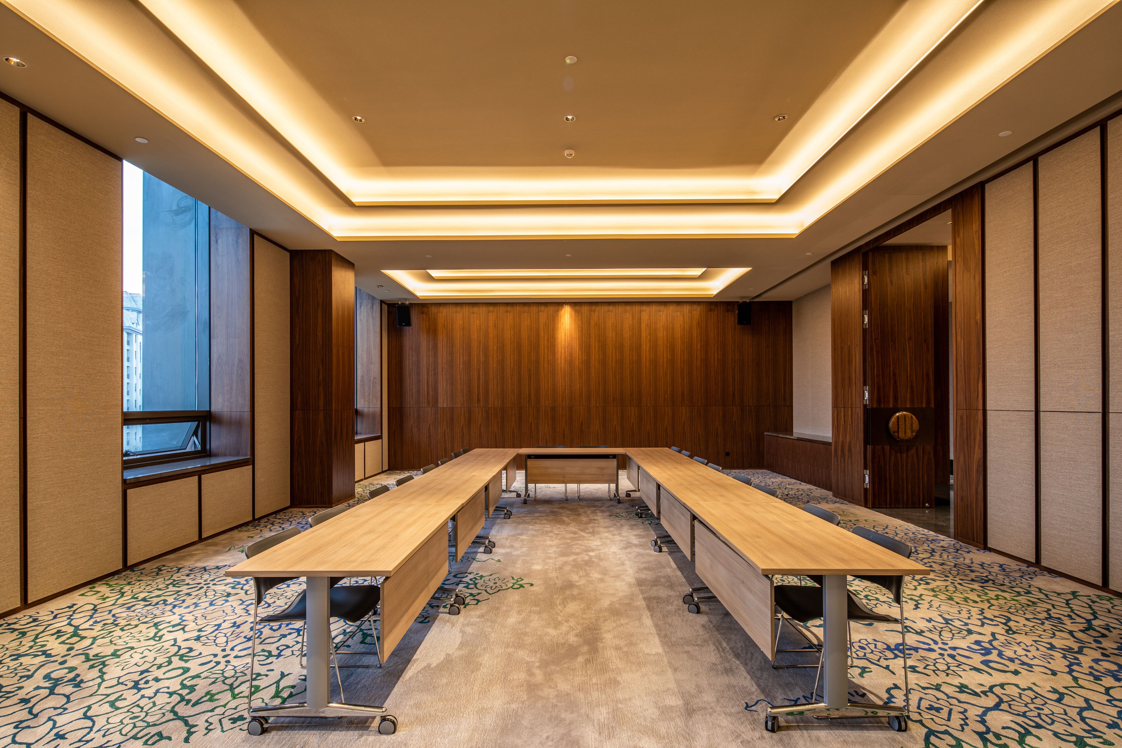 A conference room with a long table, carpeted floor, and wooden panel walls.