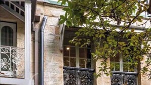 A stone building with a number '155' on the facade, decorative iron window grills, and a small balcony with white railings. - A Touch of Soho: Luxurious Historic Residence (Darlinghurst)