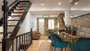 A modern interior with a staircase, a dining area with a glass table, and stone walls. - A Touch of Soho: Luxurious Historic Residence (Darlinghurst)