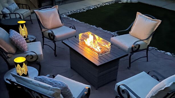 An outdoor patio with a fire pit table surrounded by cushioned chairs and decorative lanterns. - Come ride the newly opened Argo Mine Gondola and stay ahead of the traffic. (Idaho Springs)