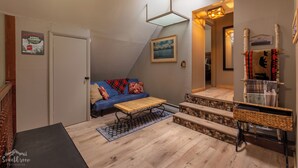 A cozy room with a blue sofa, a wooden coffee table, a woven side table, and a staircase with a wooden finish. - Come ride the newly opened Argo Mine Gondola and stay ahead of the traffic. (Idaho Springs)
