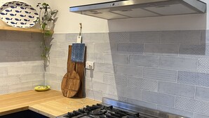 A modern kitchen with a stainless steel range hood, a gas stove, and an oven.