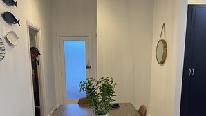 A dining area with a wooden table, chairs, a potted plant, and a ceiling light fixture.