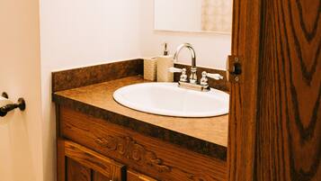 A bathroom with a wooden vanity, a white sink, and a mirror.