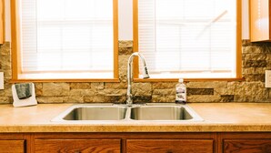 Una cocina con dos ventanas, un lavabo y armarios de madera.