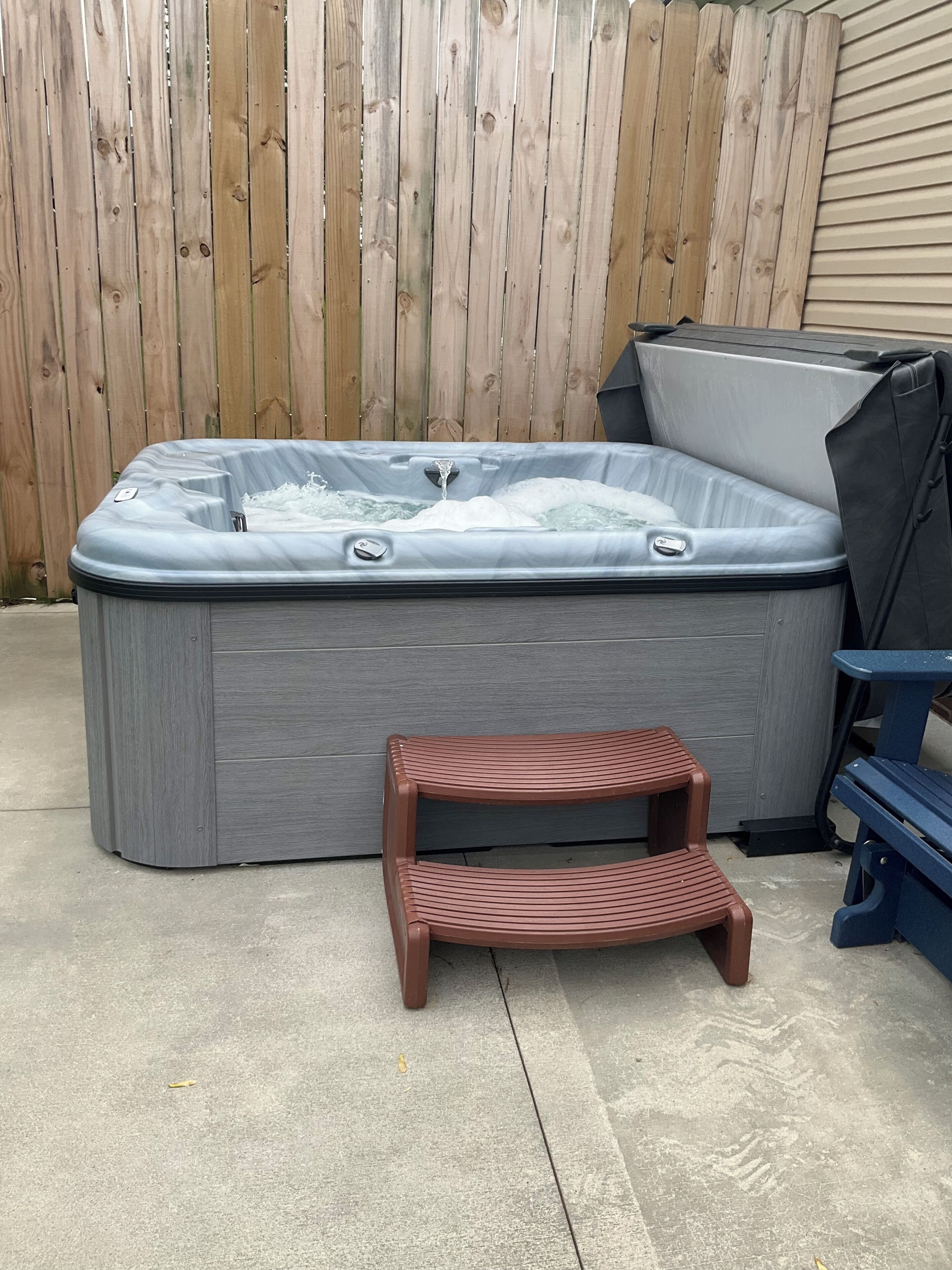 A hot tub with a wooden deck and a small wooden step.