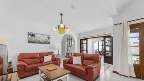 A living room with two red leather sofas, a wooden coffee table, and a chandelier. - Villa Eva - Villasexperience (Puerto del Carmen)
