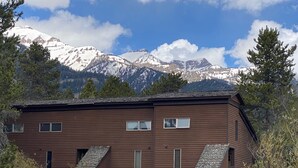 Eine zweistöckige Holzhütte mit geneigtem Dach, zahlreichen Fenstern und einer überdachten Veranda.