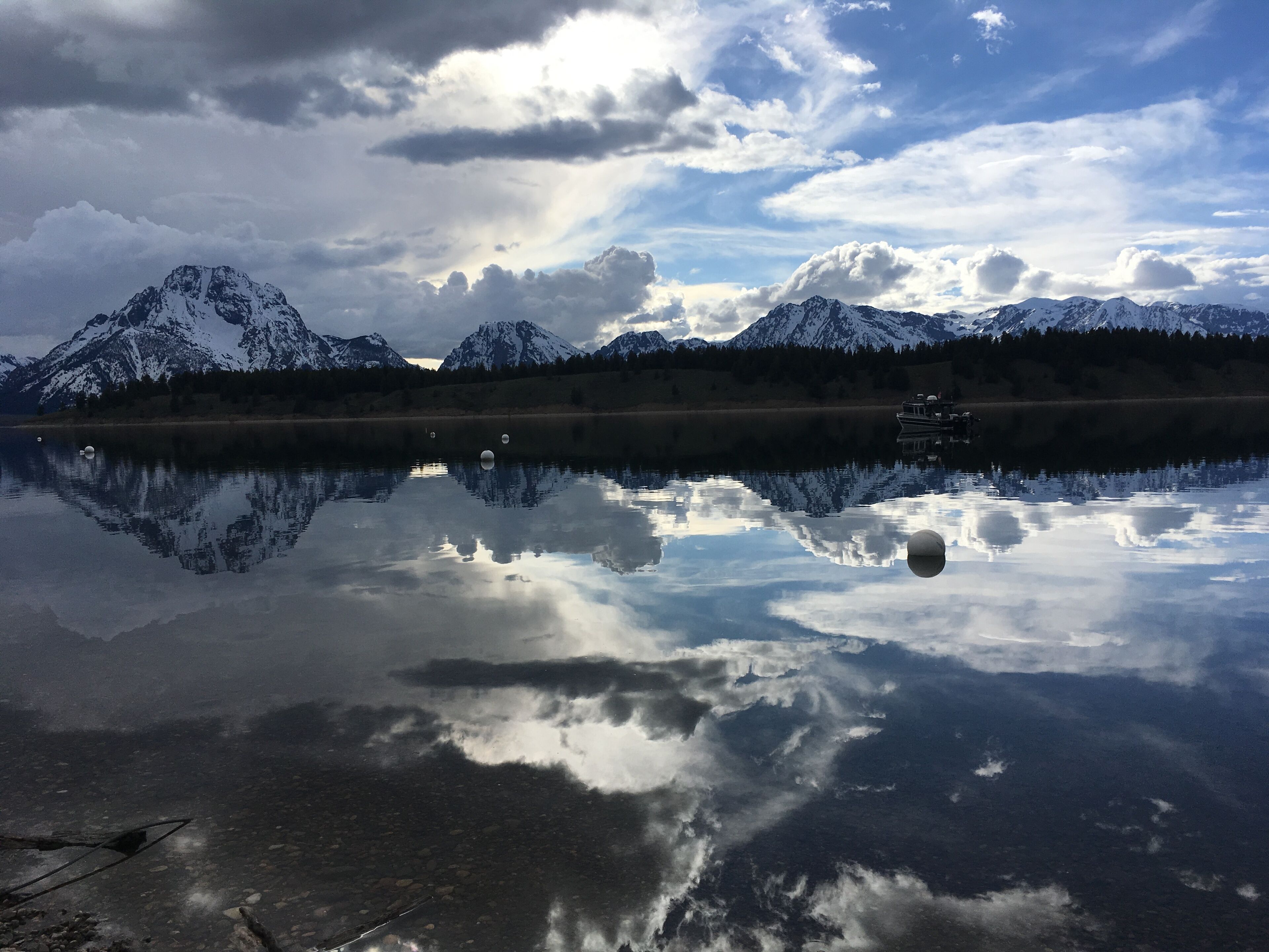 Ein ruhiger See mit schneebedeckten Bergen im Hintergrund und einem Boot auf dem Wasser.