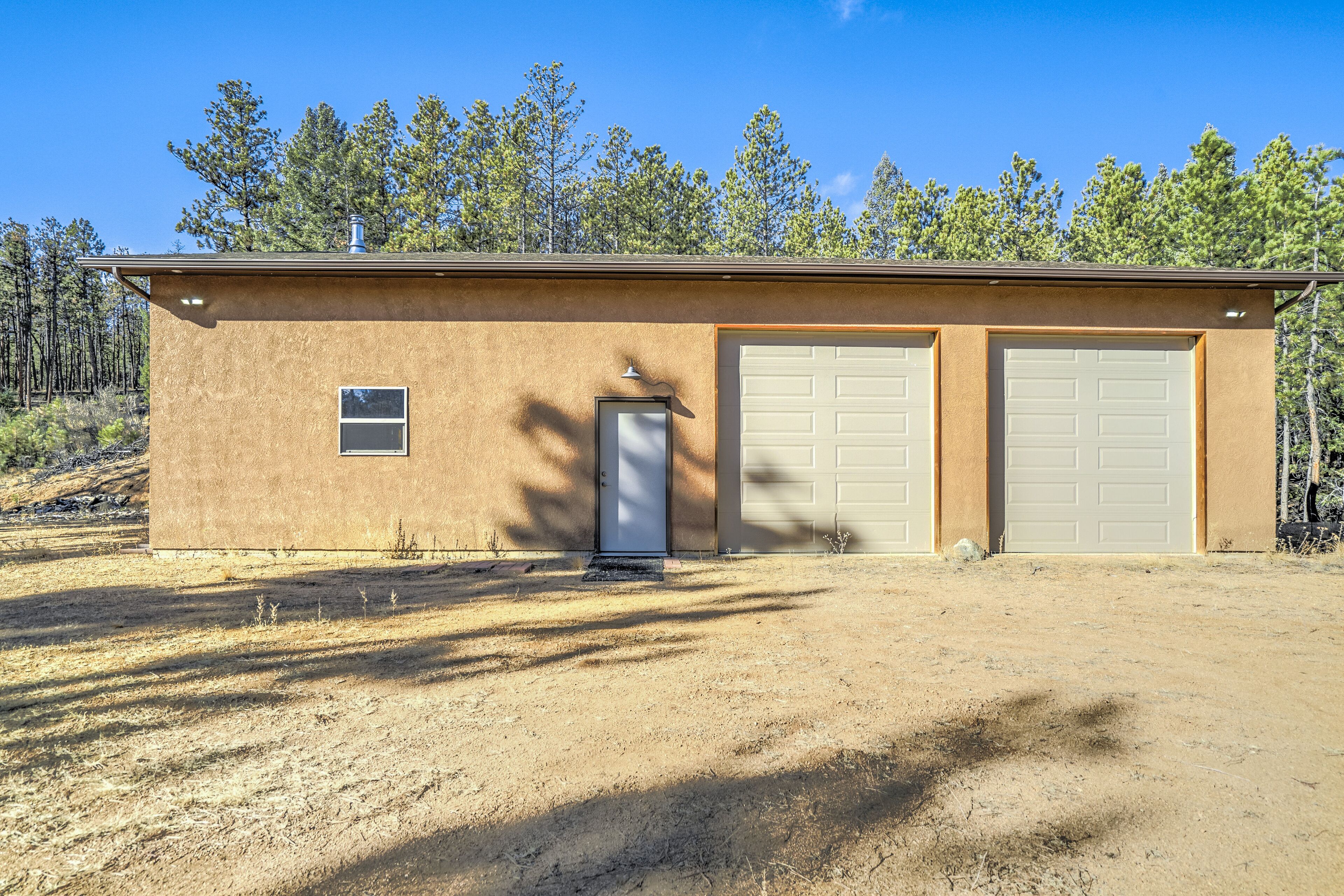 A single-story building with a brown exterior, two garage doors, and a small window.