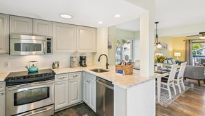Una cocina moderna con electrodomésticos de acero inoxidable, microondas integrado y cafetera.