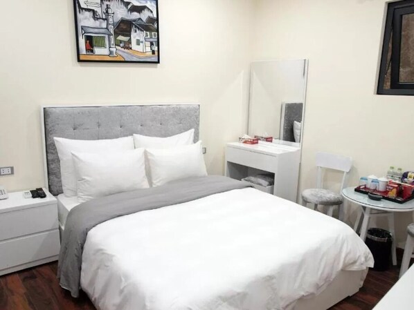 A neatly arranged hotel room with a large bed, a bedside table, a small round table, and a mirror. - VVS Glory Hotel - Bay Luxury (Hanoi)