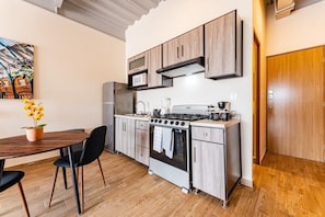 Compact kitchen with gas stove, oven, and microwave, adjacent to a dining area with a table and chairs.
