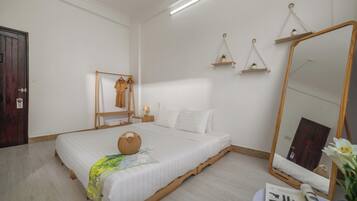 Une chambre à coucher bien rangée, avec un lit, une table de chevet, un miroir et des étagères murales.