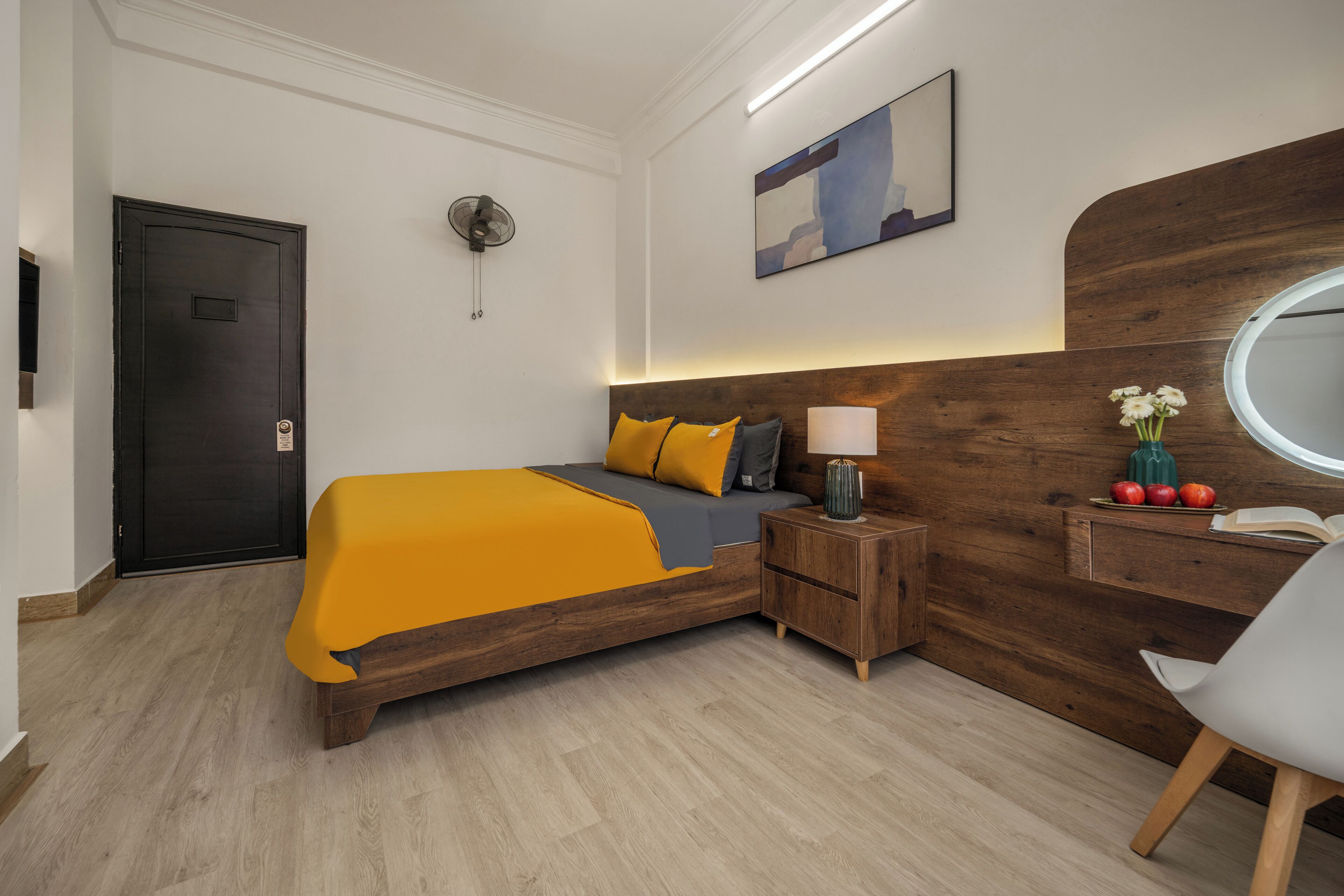 Een moderne slaapkamer met een houten bed, een nachtkastje met lamp, een spiegel en een kleine plant.