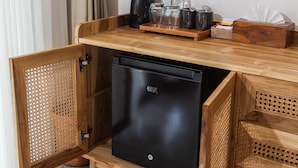 Une cuisine compacte dotée d’un réfrigérateur encastré, de meubles de rangement en bois et d’un plan de travail agrémenté d’ustensiles de cuisine.