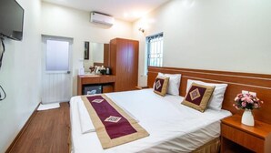 Ein Hotelzimmer mit Bett, Nachttisch und Ventilator.