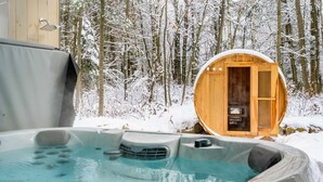 A hot tub with a wooden sauna structure in a snowy forest.