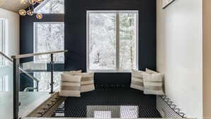 A modern staircase with a black and white color scheme, leading to a seating area with a view of a snowy landscape through large windows.