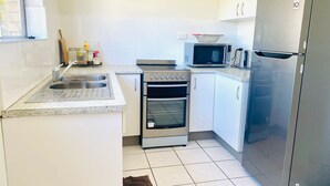 Cocina compacta con pileta, estufa, horno, microondas y refrigerador.