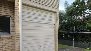 Puerta de garaje con el número 6 en la pared, una ventana y un poste de electricidad con cables.