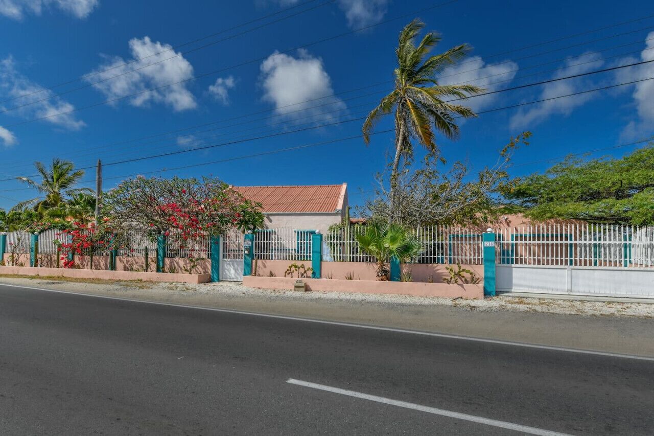 Un quartier résidentiel avec une maison, des palmiers et une clôture.