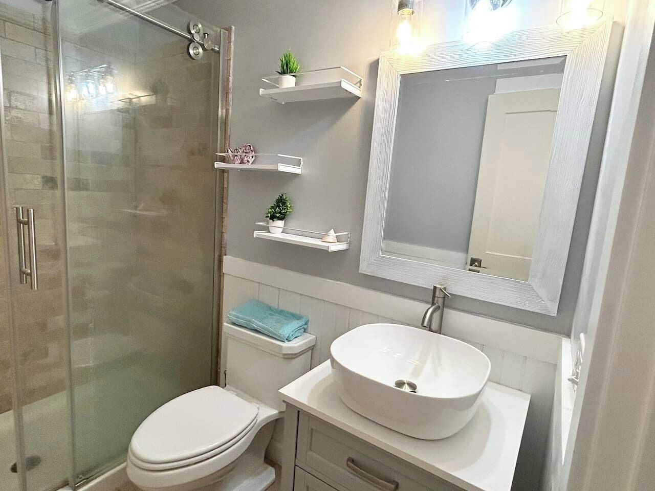 A bathroom with a glass-enclosed shower, a white sink, and a toilet.