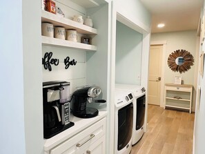 A laundry room with a coffee maker and a washing machine.