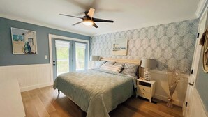 A bedroom with a bed, nightstands, a ceiling fan, and a window. - Perfect Vacation on Fripp (Fripp Island)