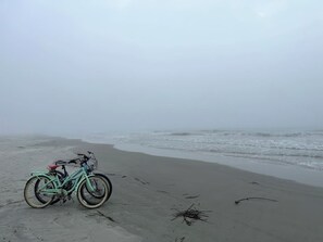 En cykel parkerad på en sandstrand med havet i bakgrunden.