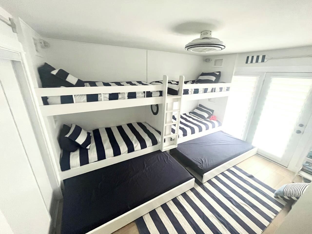 A bunk bed room with a ceiling fan, a sliding door, and a window.