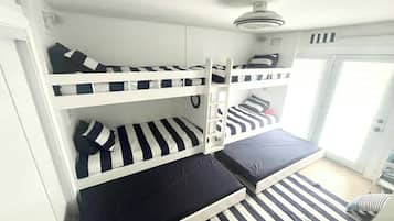 A bunk bed room with a ceiling fan, a sliding door, and a window.