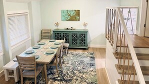 A dining area with a wooden table set for four, a teal cabinet, and a ceiling fan. - Perfect Vacation on Fripp (Fripp Island)