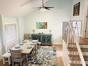 A dining area with a wooden table set for four, a teal cabinet, and a ceiling fan.