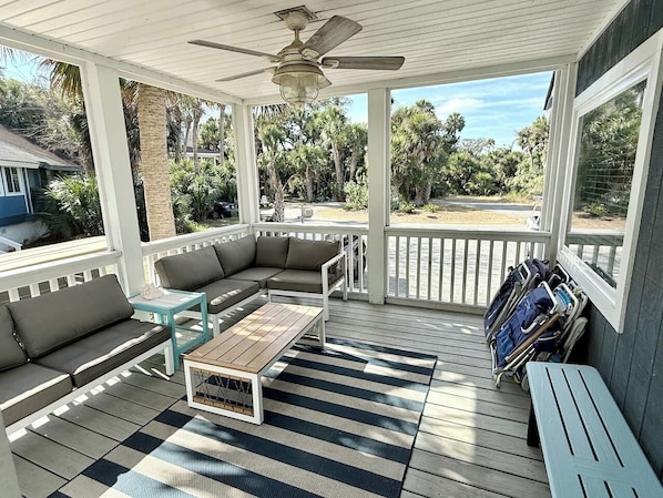 A covered outdoor area with a wooden deck, a sofa set, a table, and a ceiling fan. - Perfect Vacation on Fripp (Fripp Island)
