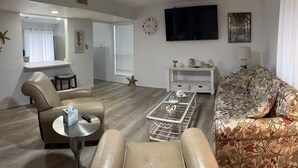 A living room with a sofa, a coffee table, and a television. - B2 Boujee, a ground floor, cozy condo, just a short walk to the beach.. (Gulf Shores)